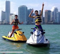 two people on jet skis in the water with a city in the background