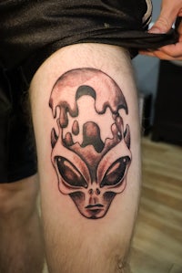 an alien tattoo on a man's thigh