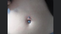 a close up of a woman's belly with a blue piercing