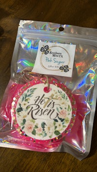 a gift tag with a pink flower on it sitting on a table