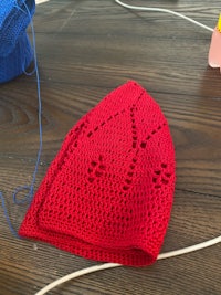 a red crocheted hat on a wooden table