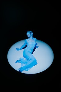 a woman in a white dress laying on a blue circle