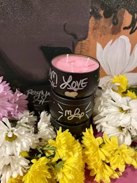 a black candle surrounded by flowers and a painting