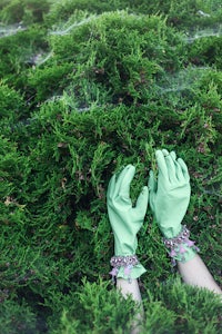 a pair of green gloves laying on top of a bush