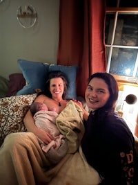 two women laying on a bed with a baby in their arms