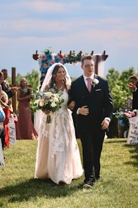 a bride and groom walking down the aisle at an outdoor wedding