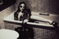a woman in sunglasses sitting in a bathtub