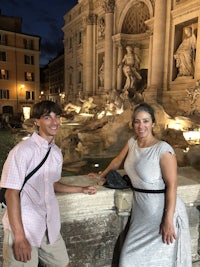 a man and a woman standing in front of the trevi fountain