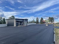 a black parking lot with trees and a blue sky