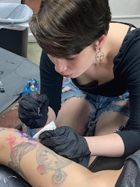 a woman getting a tattoo on her leg