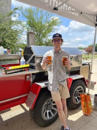 a man holding a beer in front of a trailer