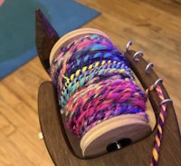 a spool of colorful yarn on a wooden spool