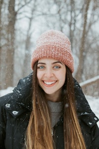 a young woman wearing a pink beanie in the snow