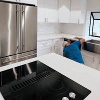 a man fixing a stove in a kitchen