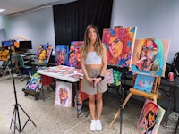 a woman standing in front of a room full of paintings