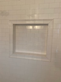 a white tiled shower with a white frame
