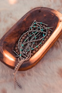 a wooden bowl with turquoise beads on it