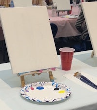 a group of people are painting on easels in a room