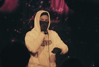 a man in a hoodie singing into a microphone