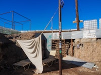 a hammock is hanging from a pole in a dirt yard
