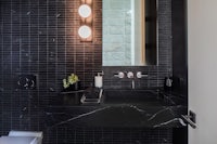 a black tiled bathroom with a toilet and sink