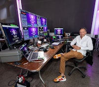 a man sitting at a desk with several monitors