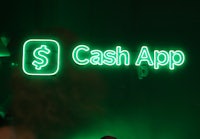 a woman is standing in front of a green sign that says cash app