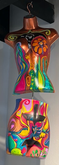 two colorful mannequins hanging from a ceiling