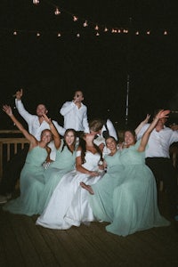 a group of bridesmaids and groomsmen posing on a deck at night
