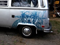 a silver vw bus with a blue face painted on it