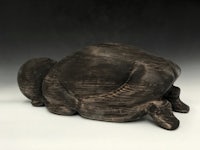 a sculpture of a turtle laying down on a white surface