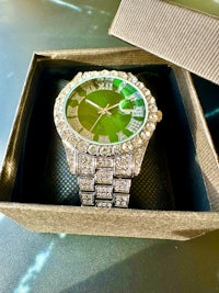 a green watch with diamonds in a box