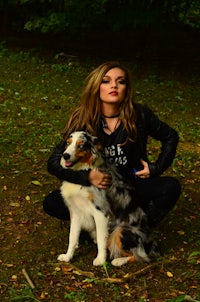 a woman posing with a dog in the woods
