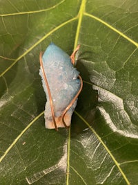 a blue druzy stone is sitting on a leaf