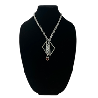 a silver necklace with a red stone on it