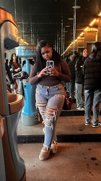 a woman in ripped jeans taking a selfie in front of a mirror
