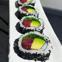 a plate of sushi with tuna, avocado and sesame seeds