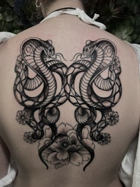 the back of a woman with a tattoo of a snake and flowers