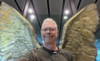 a man is taking a selfie in front of an angel wings sculpture