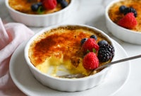 a bowl of creme brulee with berries and a spoon