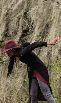 a woman wearing a burgundy hat and black jeans