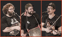four men with beards singing and playing banjos