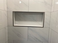 a white tiled shower with a shelf