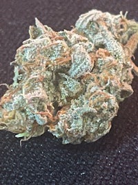 a close up of a marijuana flower on a black surface