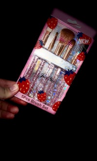 a person is holding a package of a strawberry brush set
