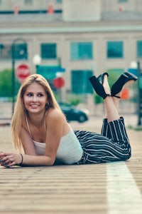 a beautiful young woman laying on a wooden boardwalk