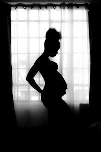 a silhouette of a pregnant woman in front of a window