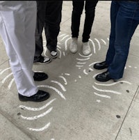 a group of people standing in a circle on the sidewalk