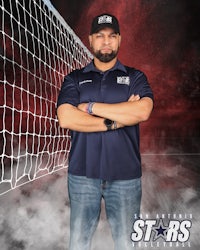a man with his arms crossed in front of a volleyball net