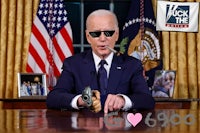 joe biden in sunglasses sitting at a desk with a gun